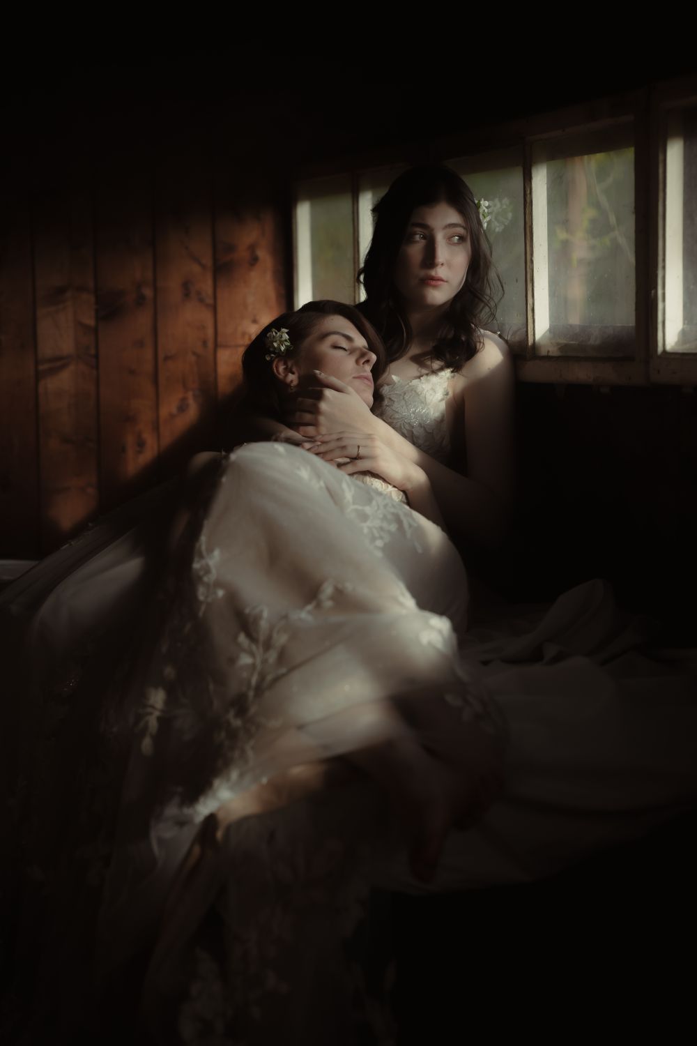 Inniger Moment zwischen zwei Bräuten, liegen am Fenster und berühren sich sanft